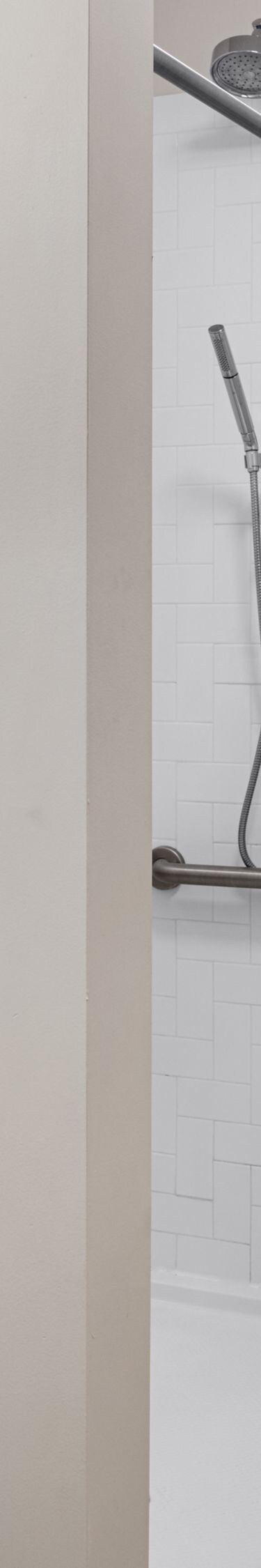 shower with grab bars, toilet, and sink