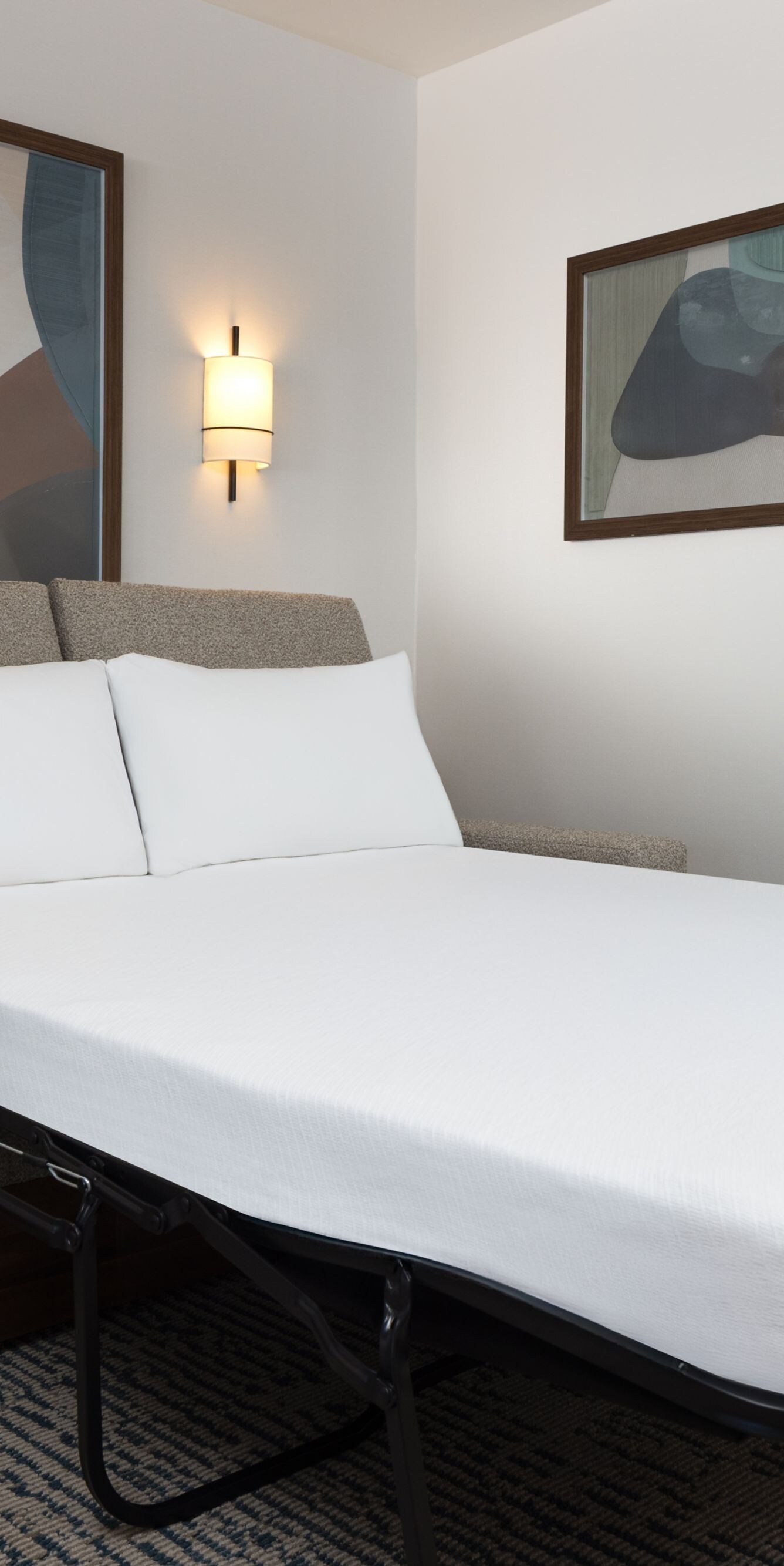 Sofa bed with white linens and wall art