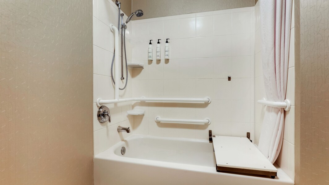 Bathtub with ADA accessible chair and hand rails. 