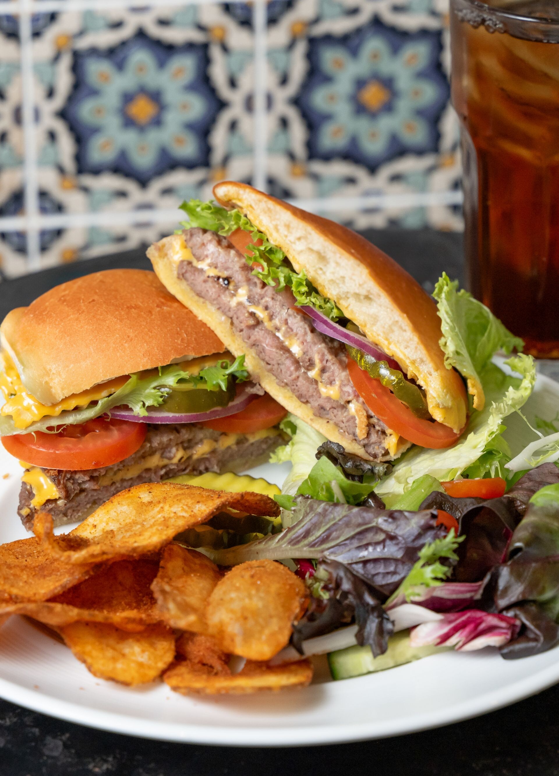 A plate with a burger, chips, salad and iced tea
