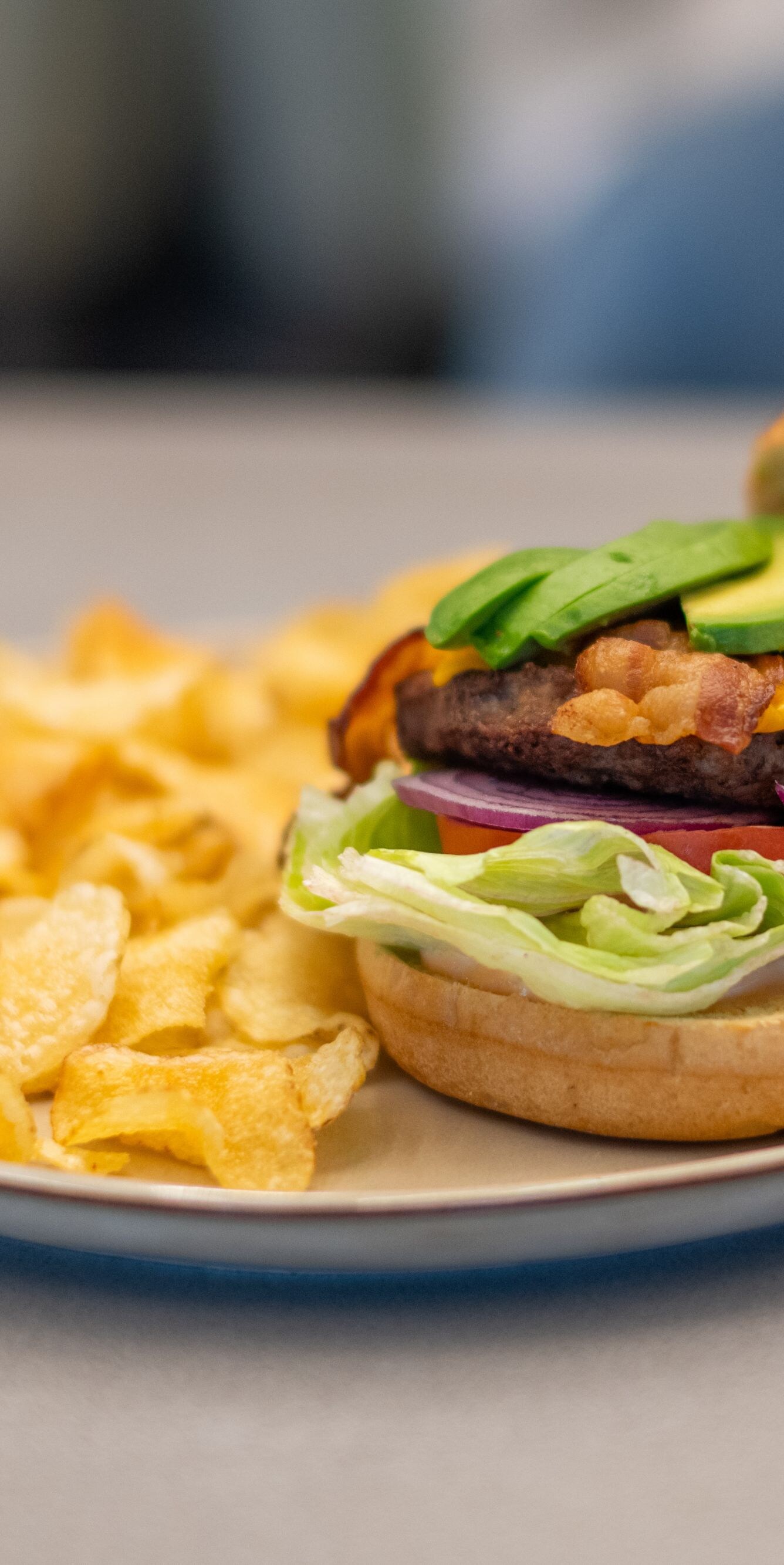Burger with bacon and avocado, served with chips