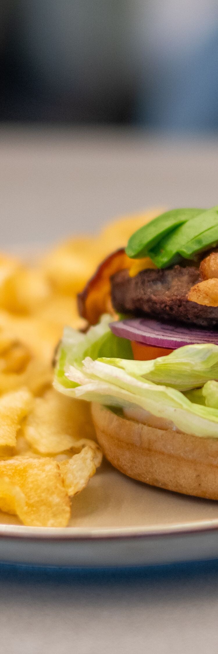 Burger with bacon and avocado, served with chips