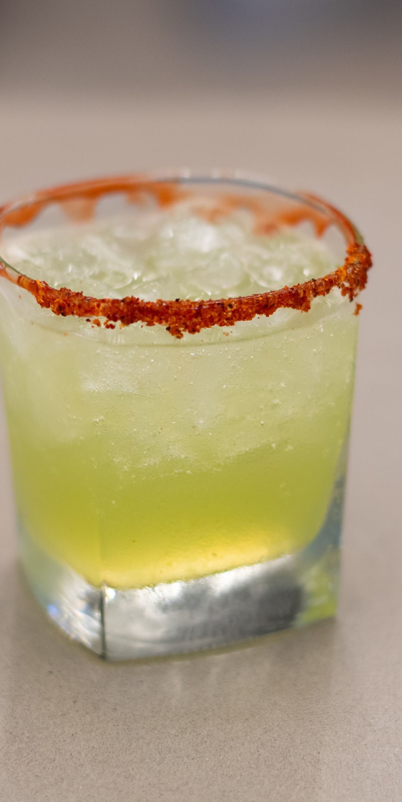 Green margarita cocktail with red chili rim