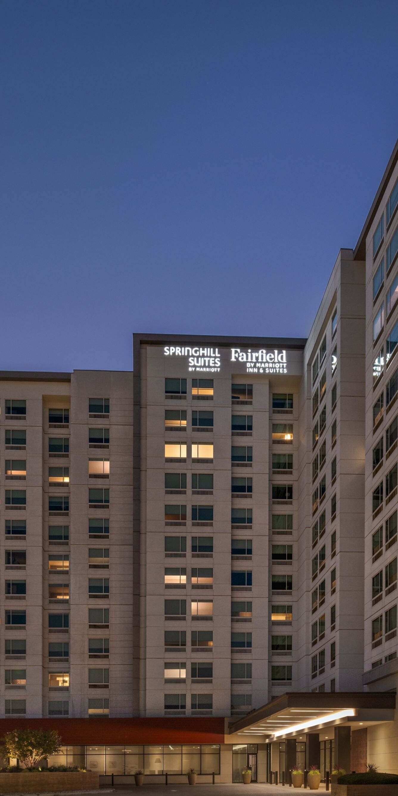 Illuminated hotel exterior and parking lot at dusk