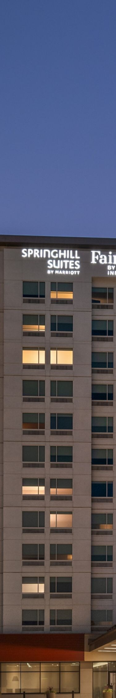 Illuminated hotel exterior and parking lot at dusk