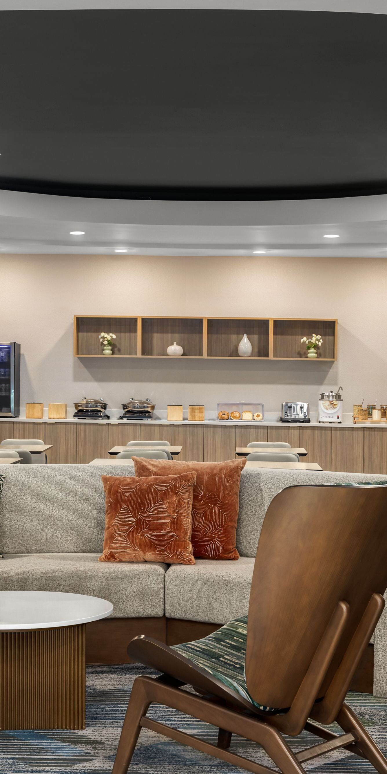 Casual lobby seating with breakfast buffet behind