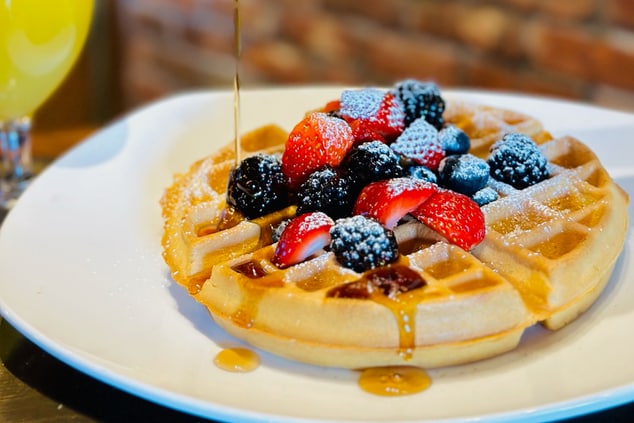 Waffle on plate with orange juice to side