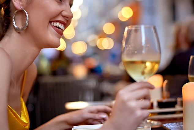 A woman is laughing and drinking wine