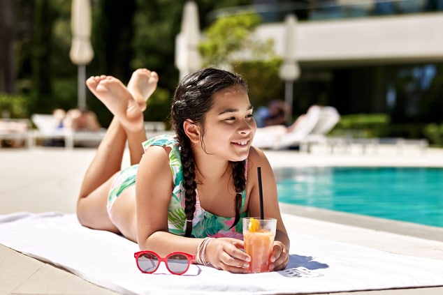 a girl with a cocktail near the pool