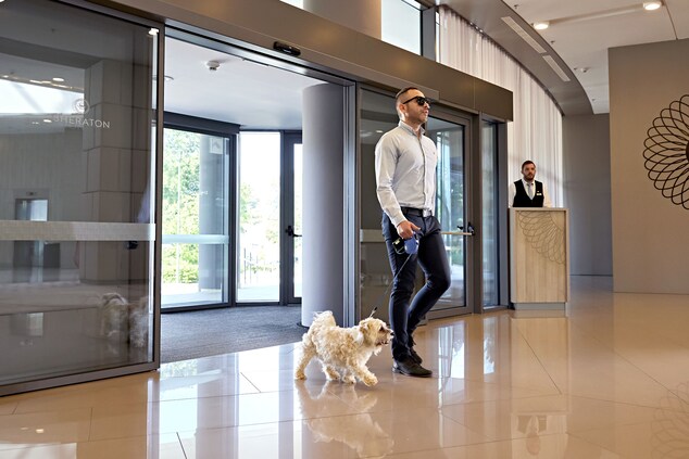 A man walking into the hotel with a white dog