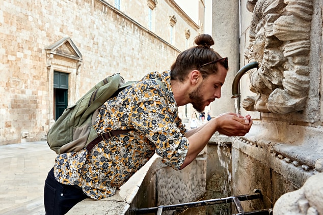 A man drinking from the historic tap 