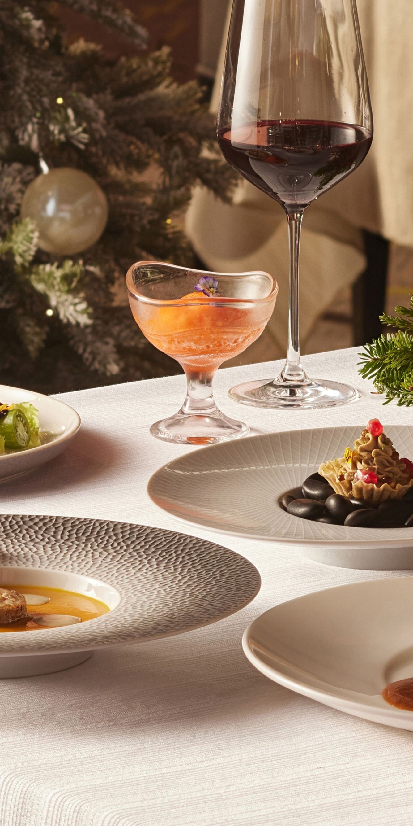 Fine dining dishes on table with Christmas decor.
