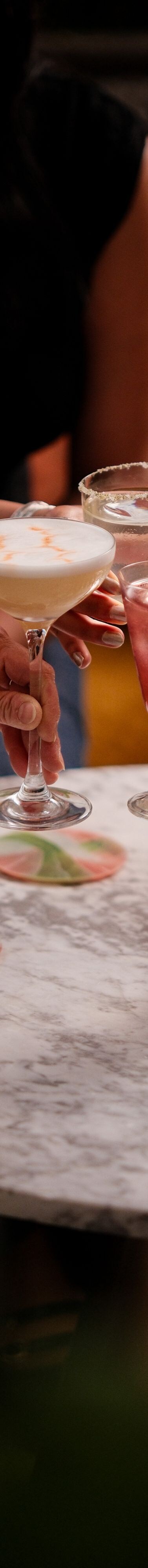 Hands holding drinks above marble table