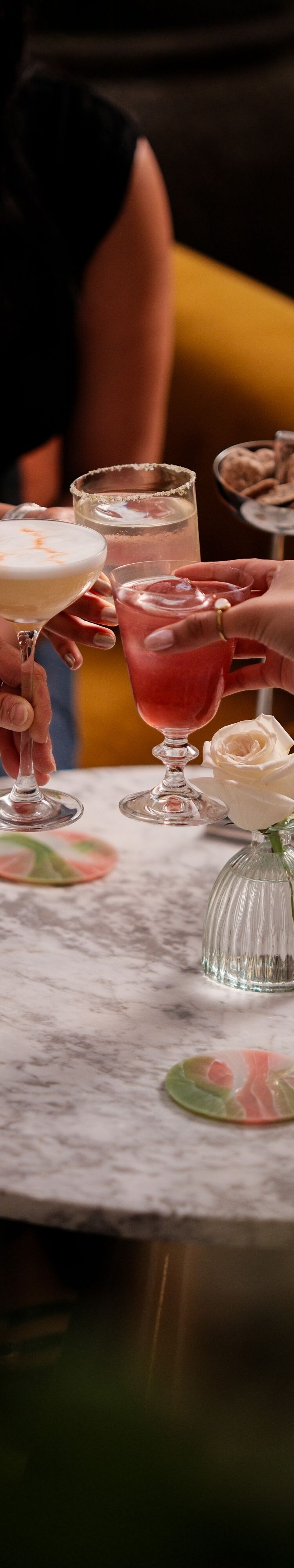 Hands holding drinks above marble table