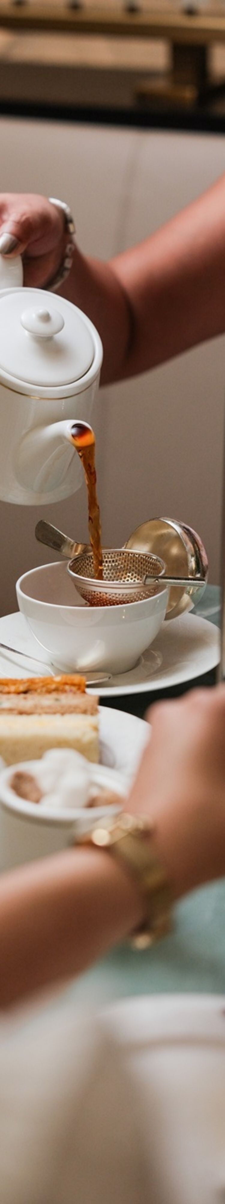 Tea poured into cup beside afternoon tea stand