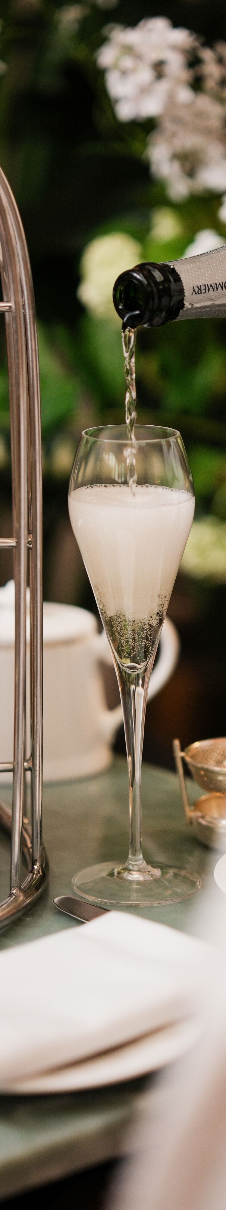 Champagne poured into flute beside tea stand