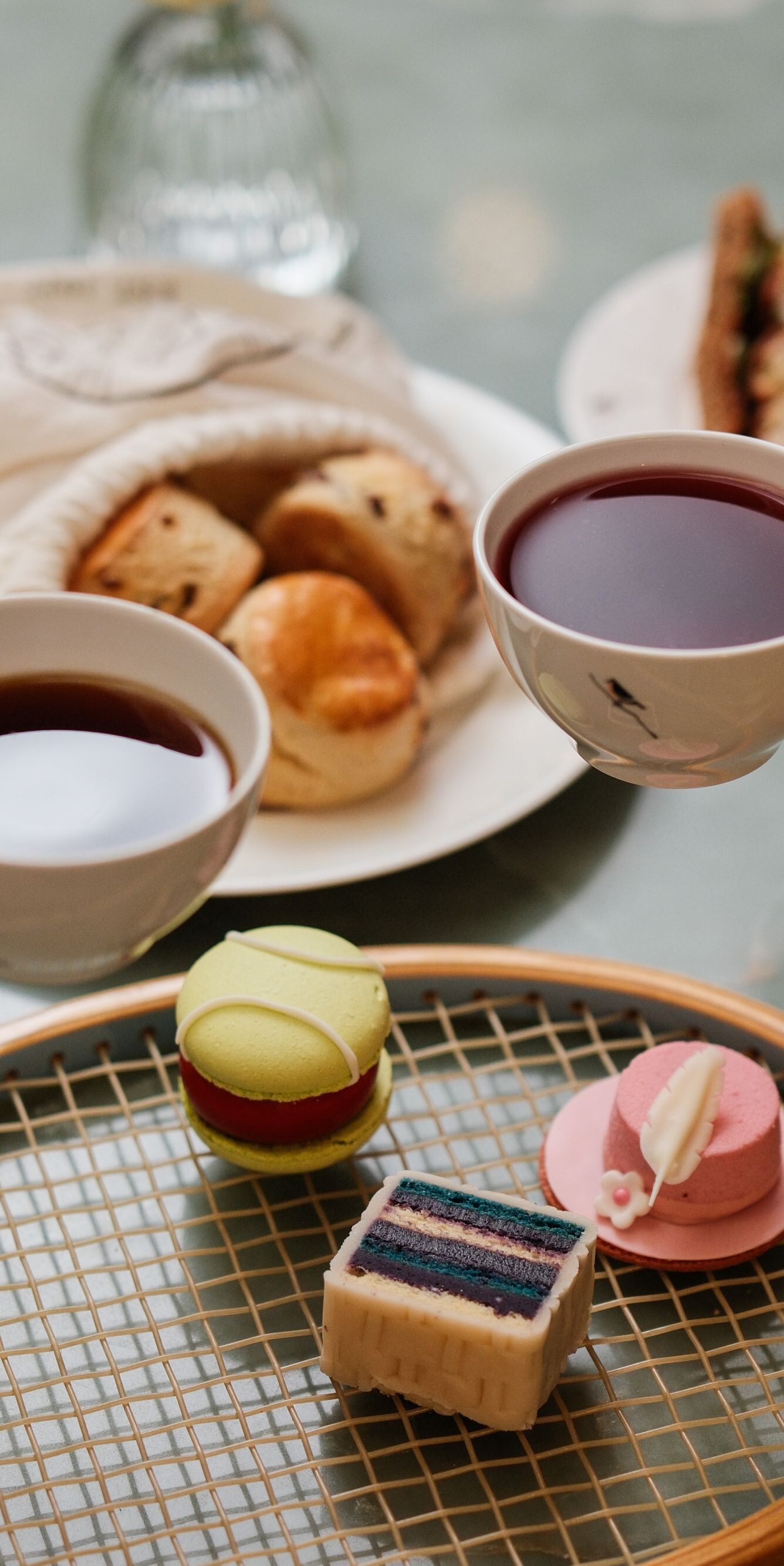 Two teacups held above afternoon tea table