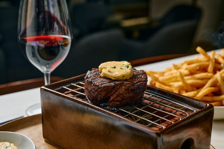 Steak on a charcoal grill with red wine and fries