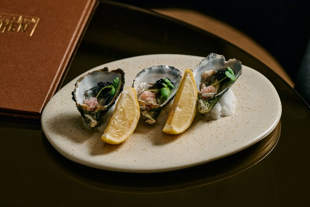 A plate of oysters with lemon wedges