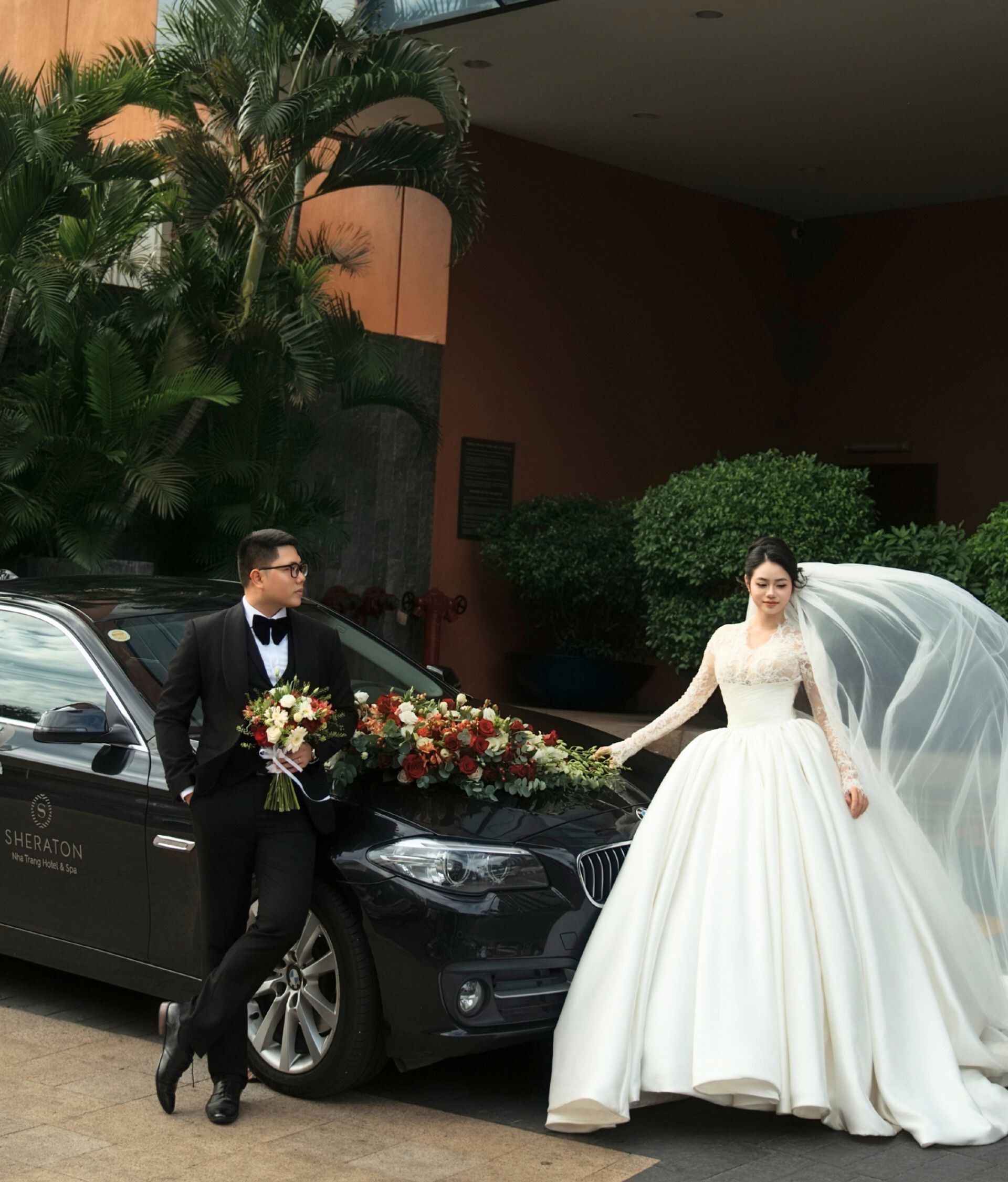 Bride and groom with car at entrance