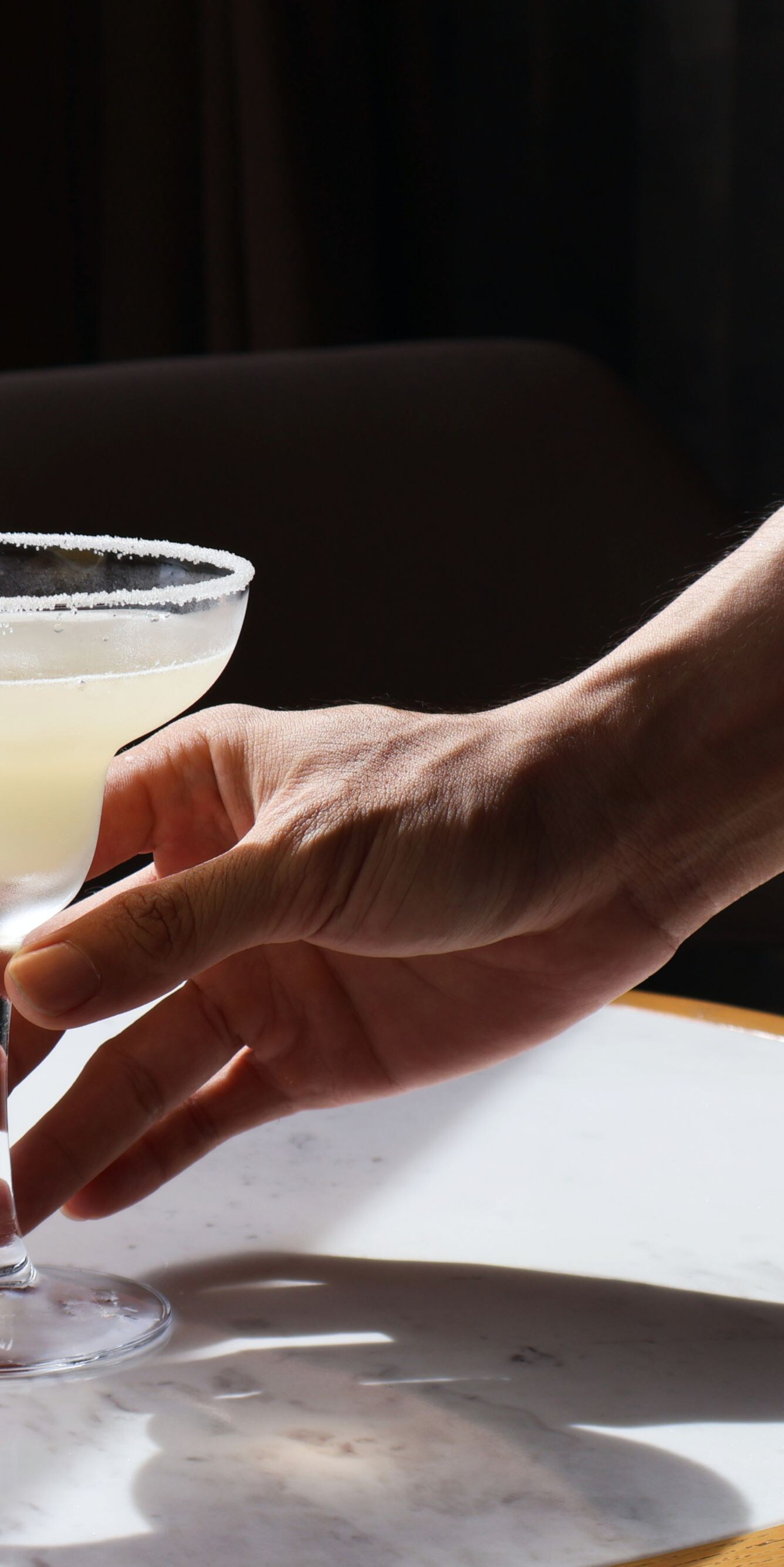 Hand holding margarita with lemon garnish
