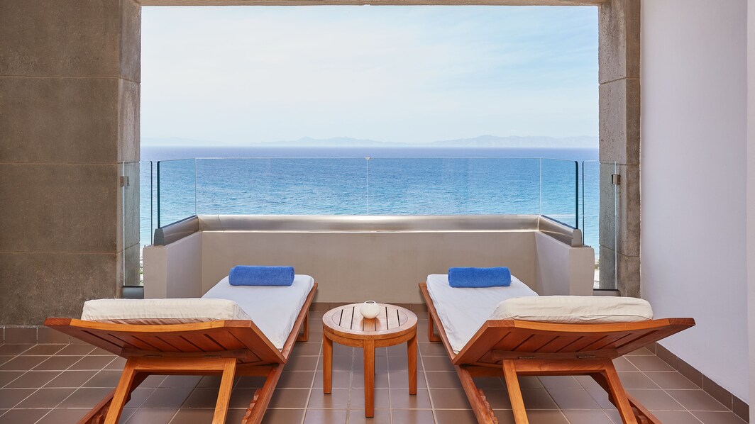 Imagen de la vista al mar del dormitorio de una suite Aelia con balcón