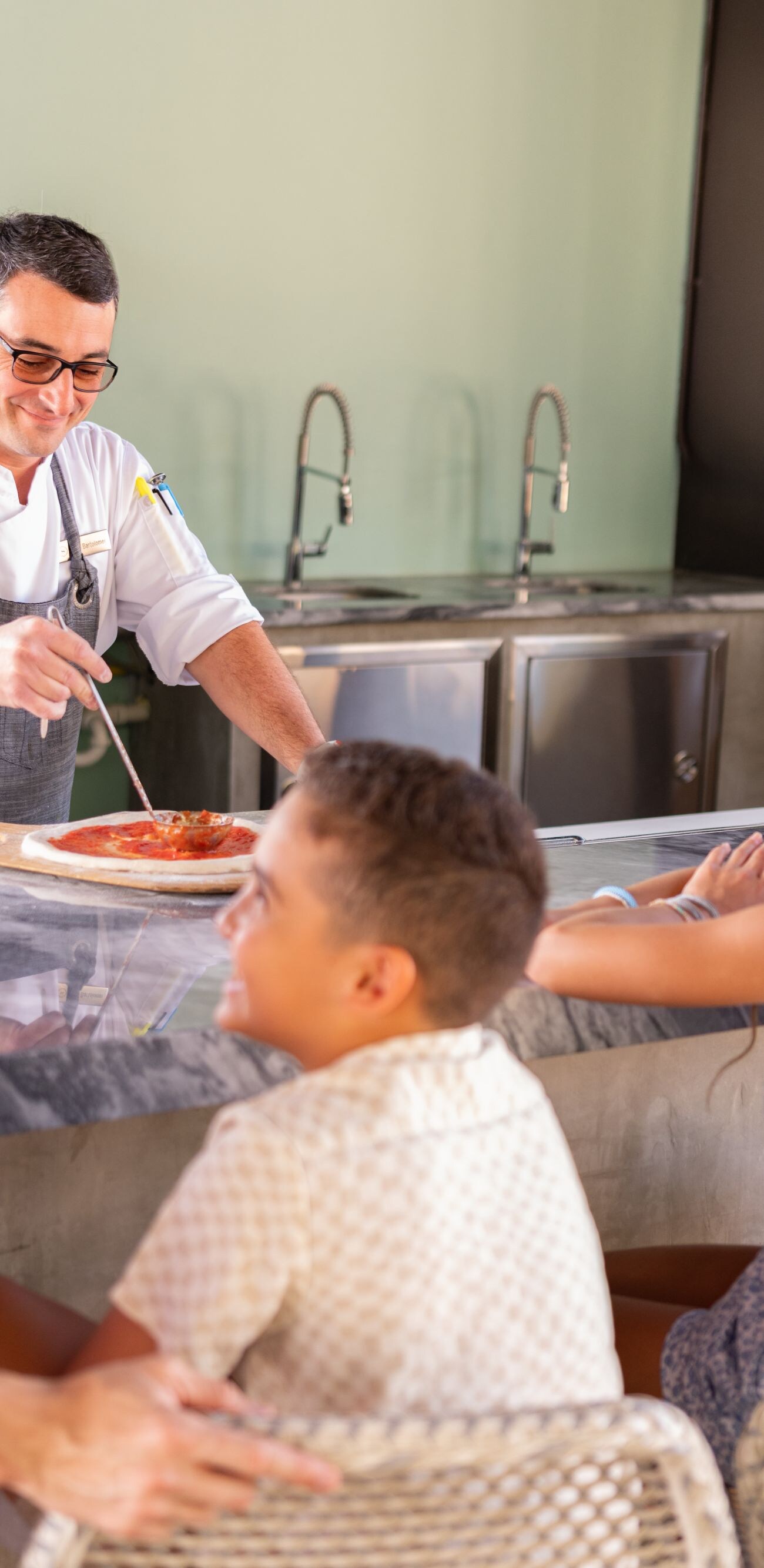Guests watching chef prepare pizza