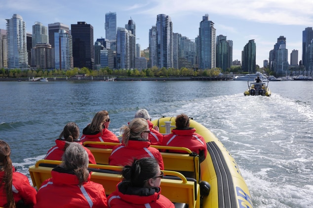 Adults on boat with a view of Vancouver's skyline.