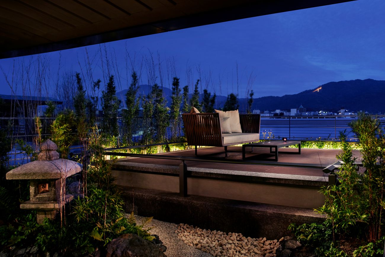 Stairs leading to an elevated outdoor deck with a sofa overlooking the river