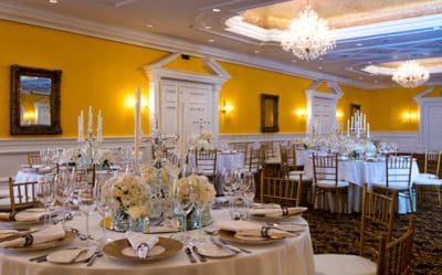 The Banquet Hall set up for a wedding reception and featuring yellow walls, white wainscoting and crystal chandeliers