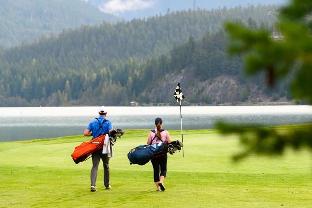 Couple with golfing gear walking on a golf course