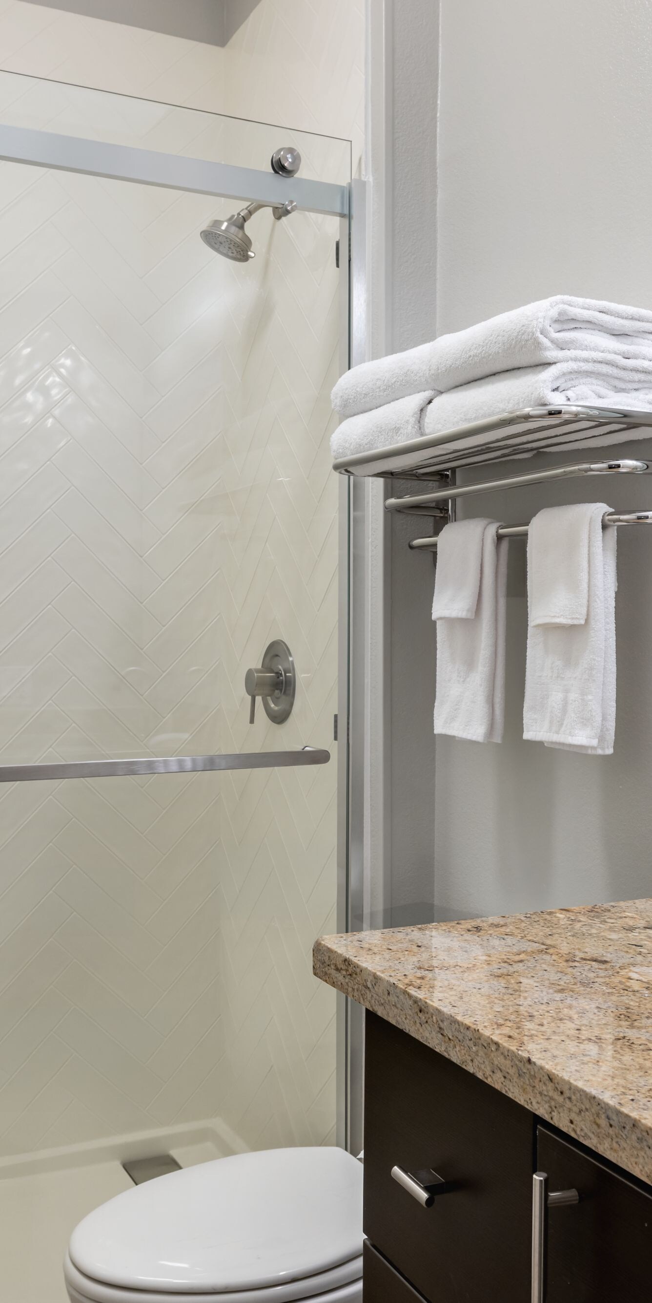 Bathroom with glass shower, sink and towels