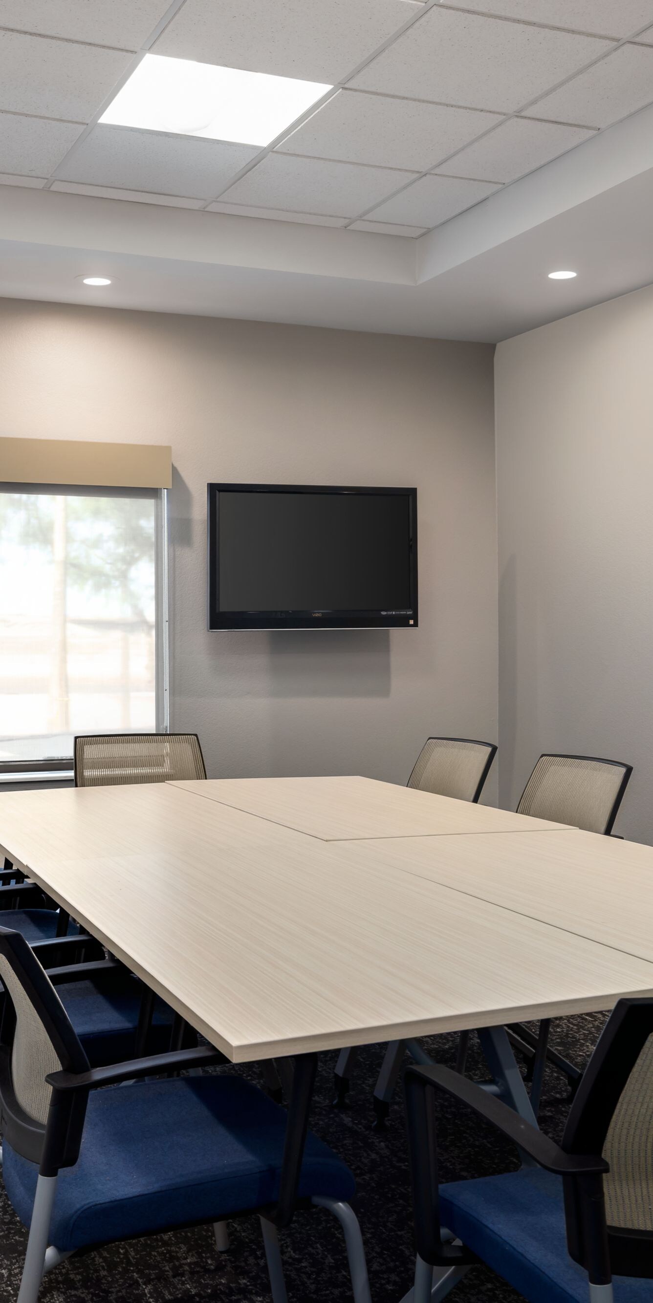 Small meeting room with table chairs and wall TV