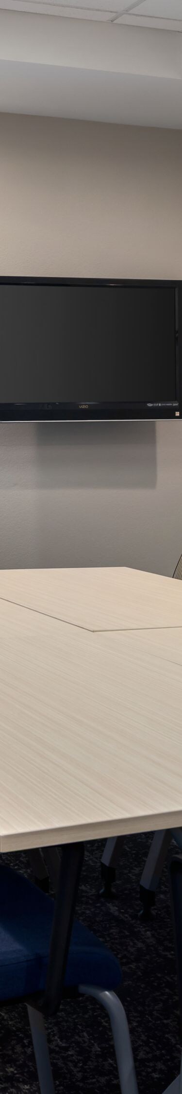 Small meeting room with table chairs and wall TV