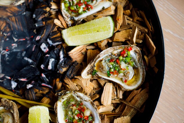 Grilled oysters on a bed of hickory chips and lime