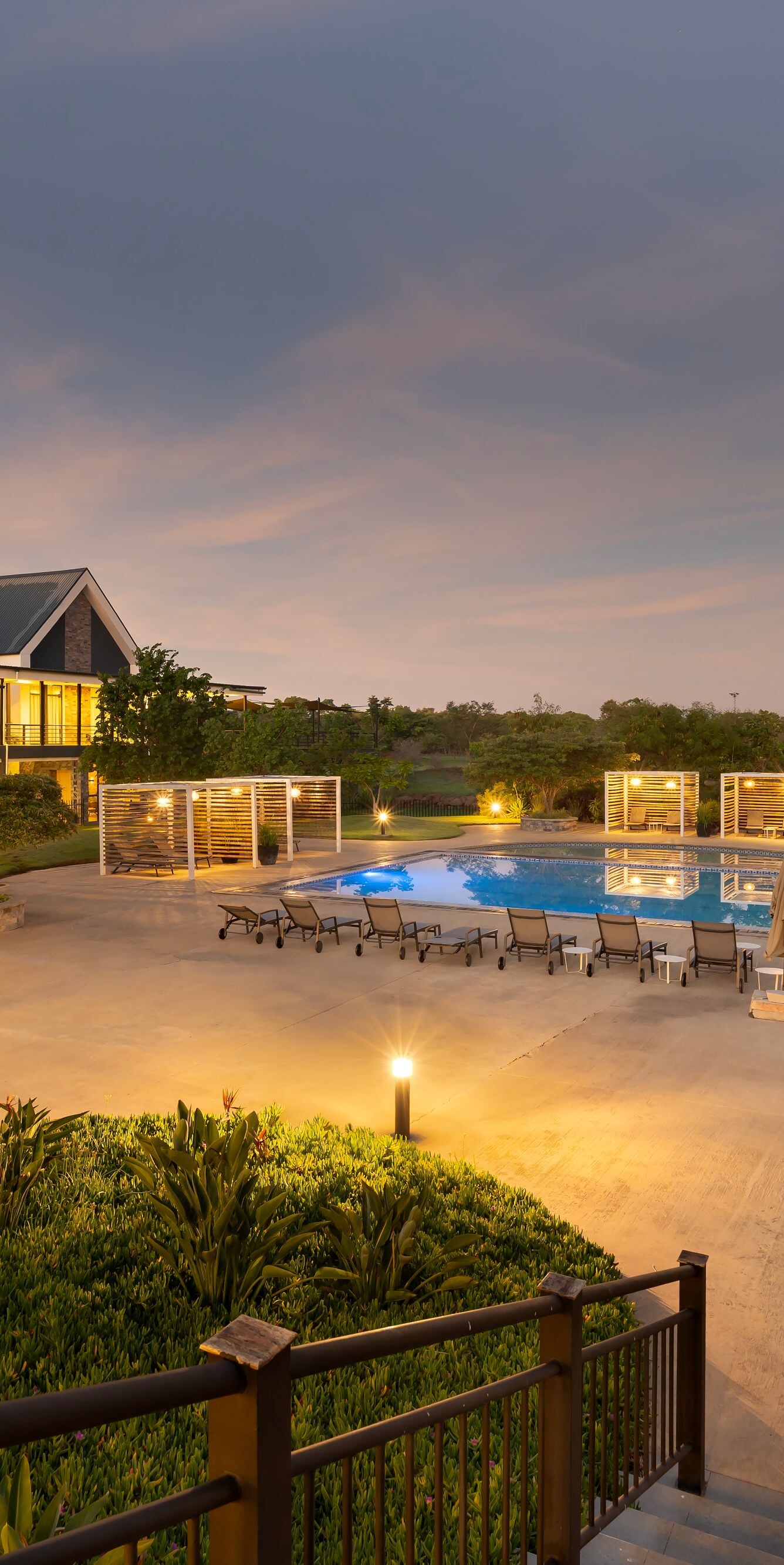 Pool at sunset with lounge chairs and lit paths