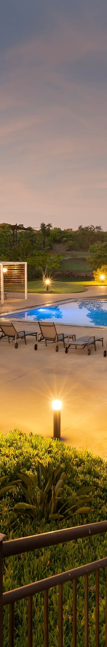 Pool at sunset with lounge chairs and lit paths