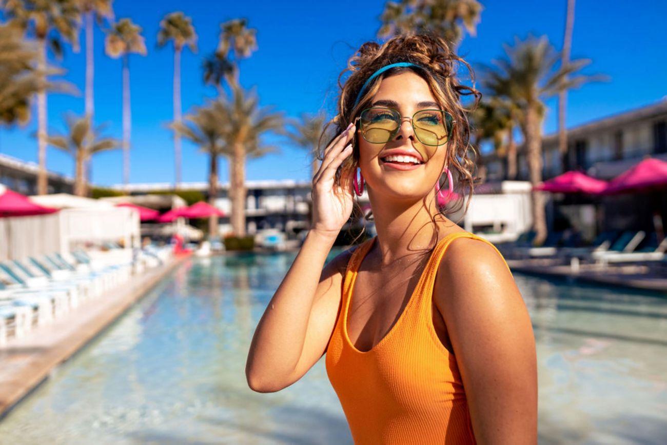 girl sitting poolside smiling with sunglasses