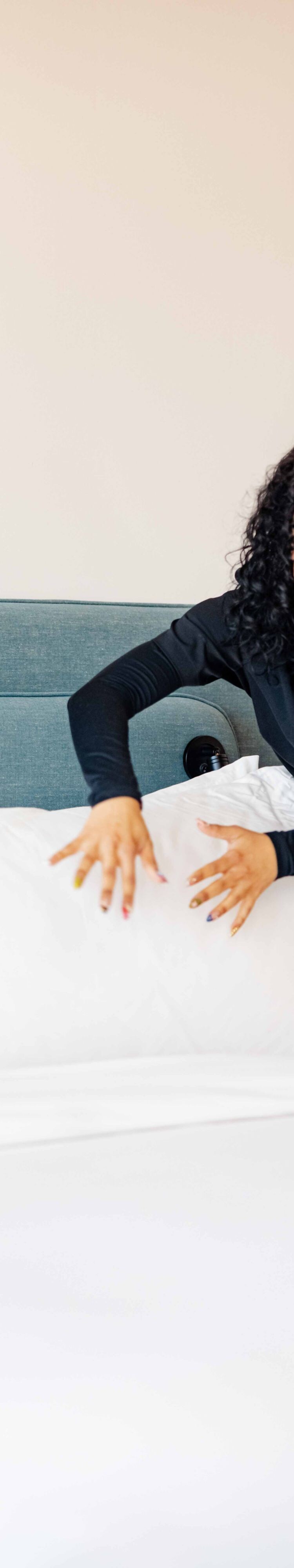 housekeeper smoothing pillow on guest bed