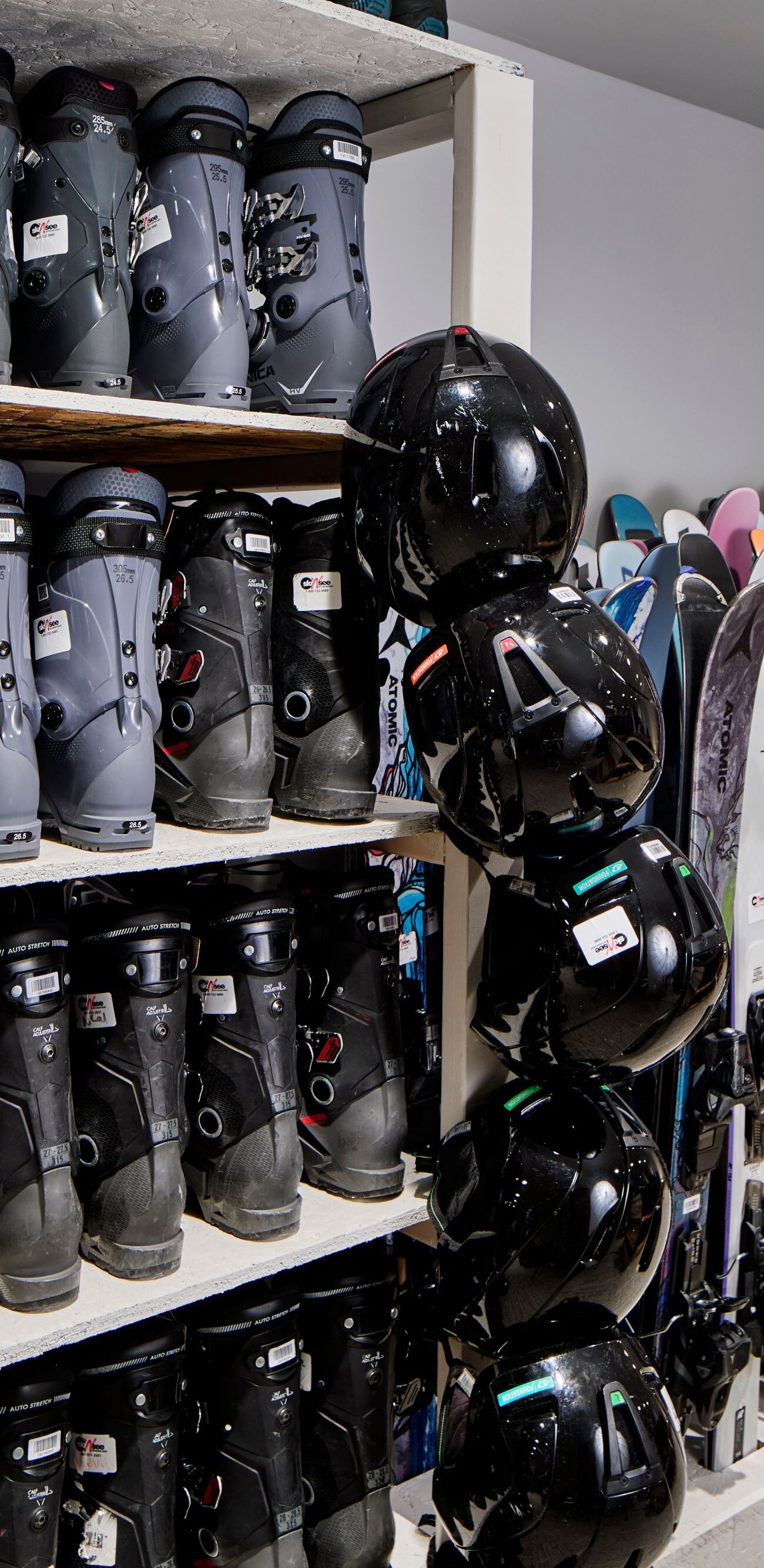 Skis, snowboards, and boots at ski rental shop.