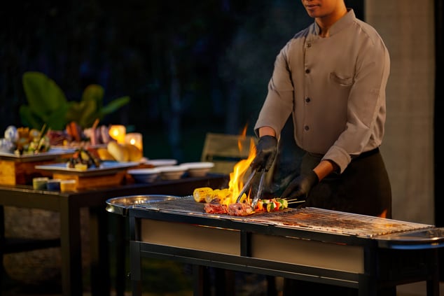 Tent-side barbecue on a grill with hotel staff