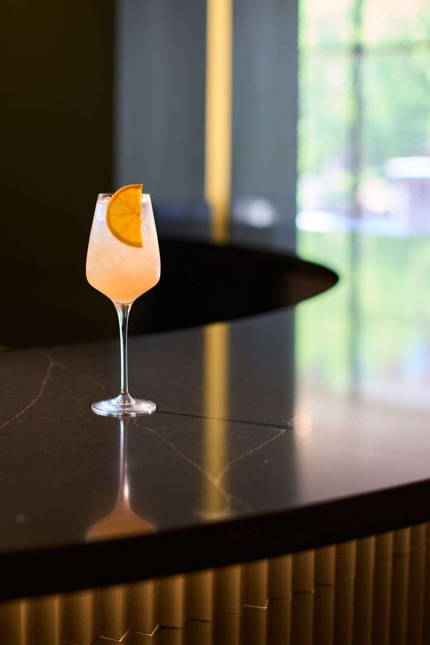 Wine glass with pink cocktail and orange wedge