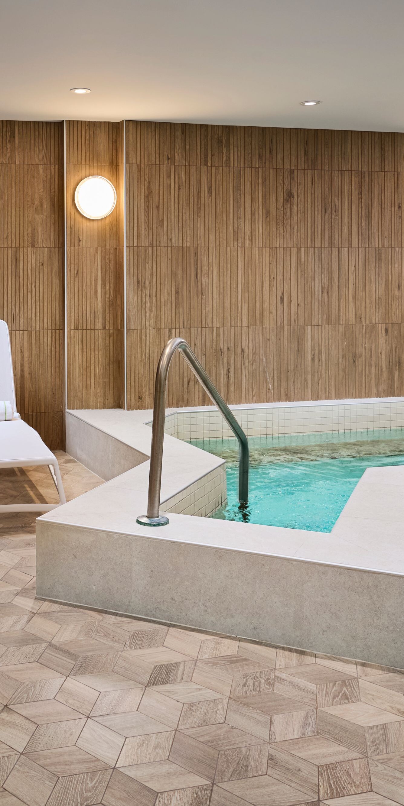 Indoor hot tub surrounded by lounge chairs.