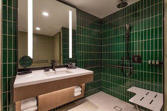 Accessible bathroom with handrails and chair.