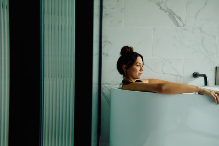 Woman in bathtub with headphones. 