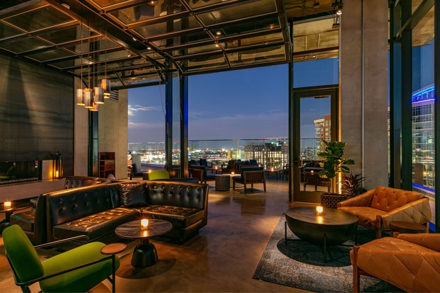 Couches and chairs by a fireplace overlooking city