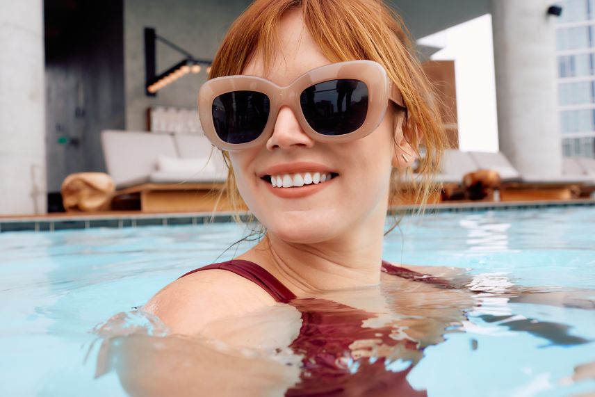 Woman in pool with sunglasses. 