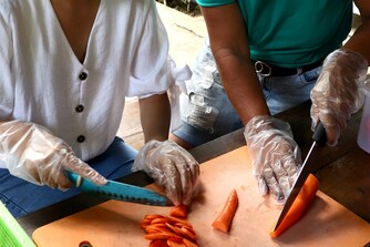 Two persons are preparing carrots