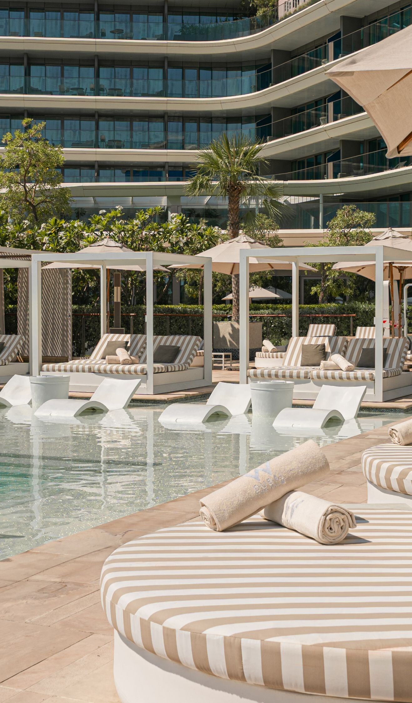 Cabanas, sunbeds, pool, and umbrella