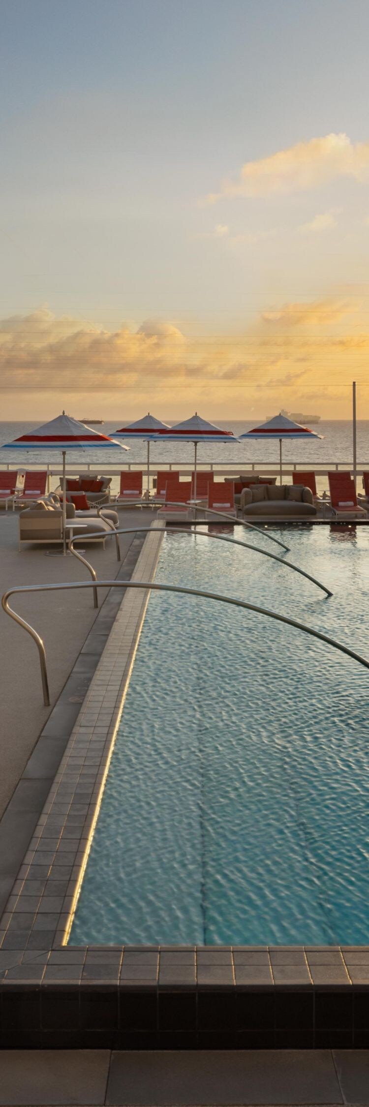 Rooftop pool at sunset with lounge chairs
